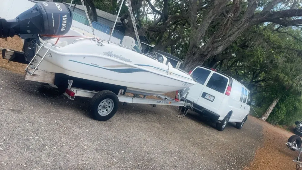 A boat on a trailer hitched to the Doorstep Deliveries van, ready for transport