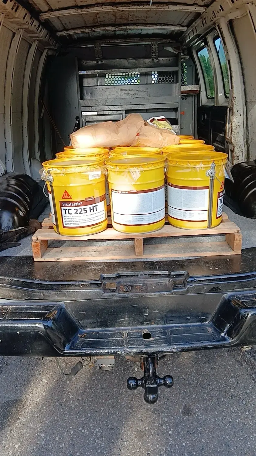 Buckets of Sika construction adhesive on a pallet, loaded for a jobsite delivery